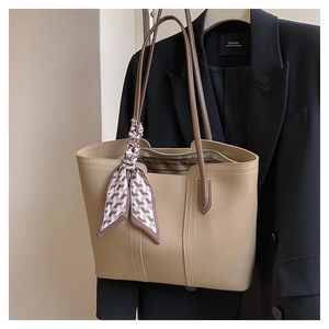 Detail of beige faux leather tote bag with houndstooth scarf and brown handles