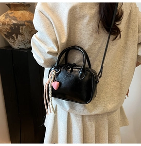 Détail d'un sac à main noir brillant avec gaufrage PAN TOR et breloque en cœur