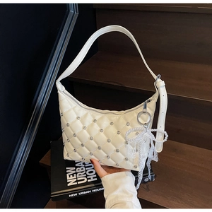 Détail du sac matelassé blanc avec rivets argentés et breloque noeud en perles