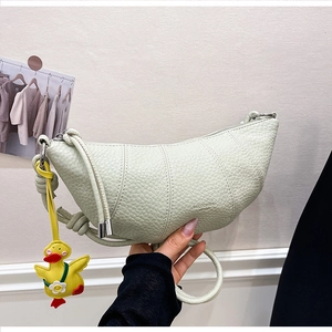 Detail shot of light green croissant bag with lychee texture and duck charm