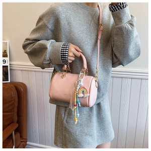 Detailed macro shot of pink pebbled leather Boston bag with rainbow keychain and gold hardware