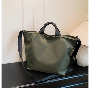 Detail of dark army green nylon tote bag with black handles and adjustable shoulder strap
