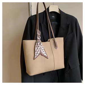 Detail of beige large tote bag with lychee texture and silk scarf on a black blazer