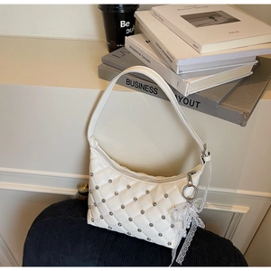 Détail du sac matelassé blanc avec clous argentés et nœud en dentelle et perles