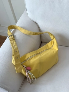 Lightweight bright yellow crescent crossbody bag with wide adjustable strap and charm