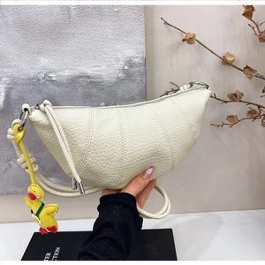Detail of creamy white pebble leather croissant bag with stylish duck charm and metal ring