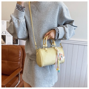 Close-up of a pale yellow Boston bag with lychee texture and rainbow ribbon accessory