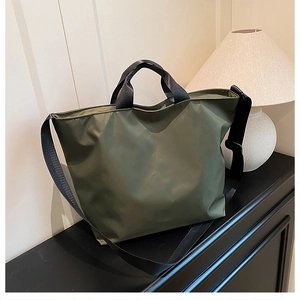 Detail of dark green tote bag featuring durable nylon fabric and reinforced black handles