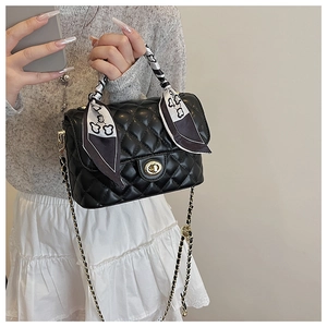 Close-up of black quilted box bag with gold twist lock and bear print silk scarf handle