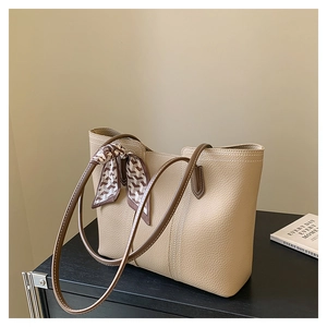 Detail of beige lychee grain leather tote bag with decorative geometric silk scarf
