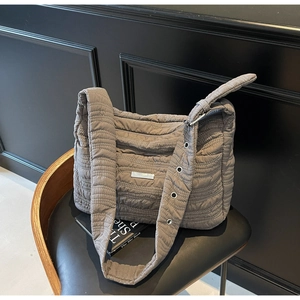 Detail of taupe quilted tote featuring a wide shoulder strap and metallic eyelets decoration