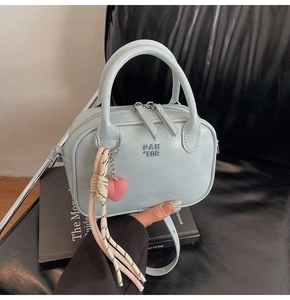 Détail du mini sac bandoulière bleu bébé avec texture cuir et pendentif cœur