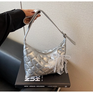 Detail of silver quilted chain bag with rhinestone studs and lace pearl bow charm