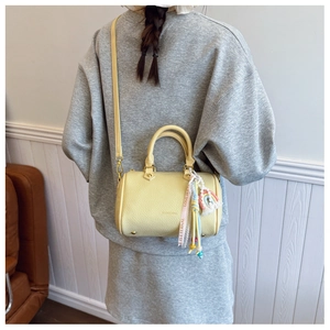 Detail view of yellow lychee leather boston bag with rainbow tassel and strap