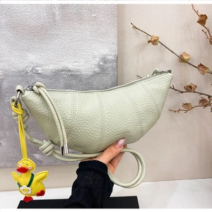 Detail view of mint green croissant bag with lychee texture and cute duck charm