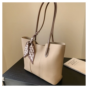 Detail of lychee textured leather tote bag with elegant checkered scarf on the handle