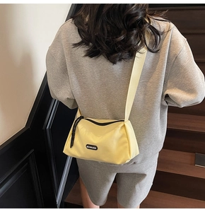 Détail de la large bandoulière réglable sur le sac à bandoulière en toile crème avec logo
