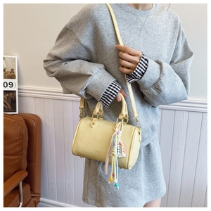 Detail of yellow lychee leather boston bag with rainbow tassel and golden hardware