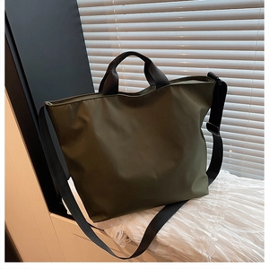 Detail of army green nylon tote bag with black handles and adjustable shoulder strap