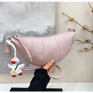 Detailed close-up of pink croissant bag with lychee texture and cute duck charm