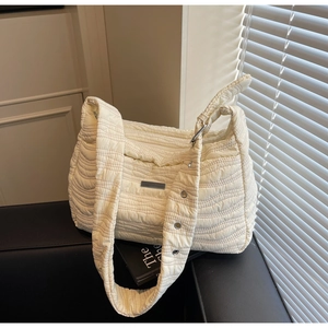 Detail of off-white quilted shoulder bag with wave patterns and metal eyelet strap