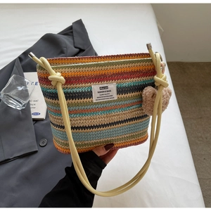 Detail of colorful striped woven bucket bag with yellow rope handles and a plush bear charm