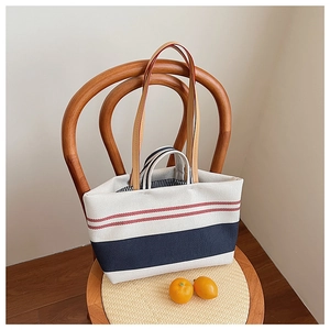 Canvas-Tragetasche mit blau-roten Streifen auf einem Vintage-Stuhl präsentiert