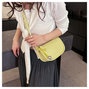 Détail du sac demi-lune jaune citron avec bandoulière tressée et pendentif coeur argenté