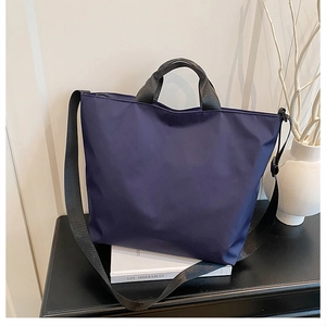 Close-up of navy blue tote bag with black handles on a table with French aesthetic props