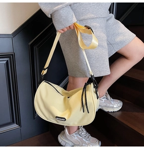 Detail of light yellow crescent nylon crossbody bag with logo and adjustable wide strap