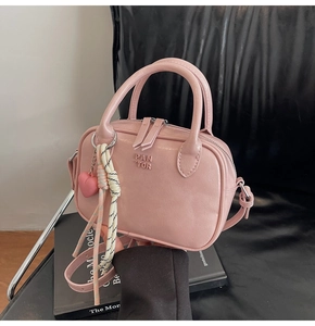 Détail d'un sac à main rose en similicuir avec logo embossé et pendentif en forme de cœur