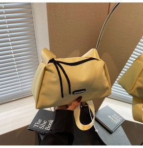 Détail du sac bandoulière en nylon jaune clair avec sangle large et logo en caoutchouc