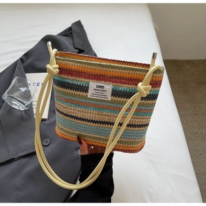 Detail of colorful striped woven bucket bag featuring knotted shoulder strap and brand label