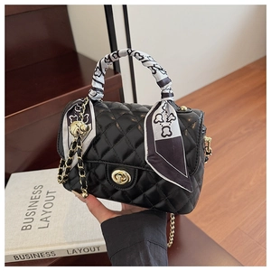 Close-up of black quilted crossbody bag with gold hardware and silk scarf on handle