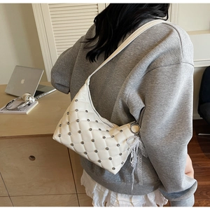 Detail of cream quilted bag with silver studs and lace pearl charm accessory