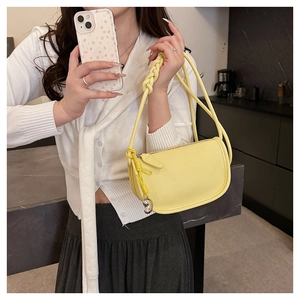 Détail du sac selle en cuir grainé jaune clair avec une poignée tissée à nœud unique