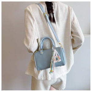 Detail of light blue pebble leather Boston bag with rainbow tassel and gold hardware