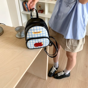 Dettaglio di un mini zaino con tasca a quadri, ricamo a mela e scritta Not Anxious
