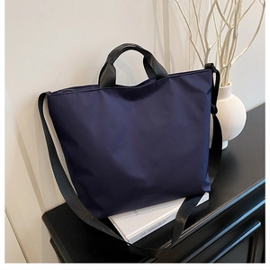 Close-up of navy blue large capacity tote bag with black handles and shoulder strap