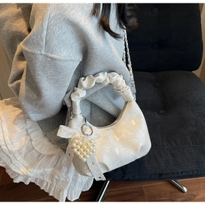 Close-up of cream crescent bag featuring pearl heart charm and lace bow detail