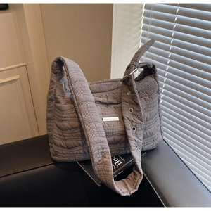 Detail of grey quilted puffy tote bag with wavy stitching and adjustable wide strap