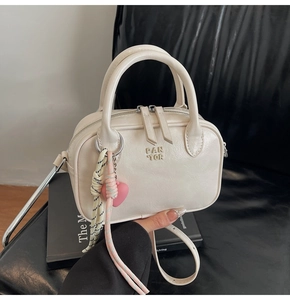 Détail du sac à main crème avec lettrage embossé et pendentif cœur rose