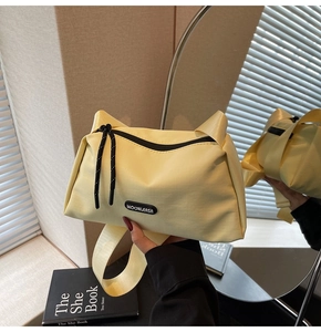 Détail du sac en toile jaune crème avec poignées en oreilles de chat et tirette tissée