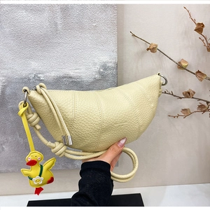 Detail of light yellow lychee grain leather croissant bag with cute duck charm accessory