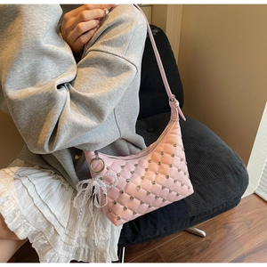 Détail du sac à bandoulière rose matelassé avec clous argentés et nœud perlé