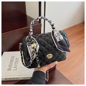 Detail of black quilted leather box bag with silk scarf handle and gold chain