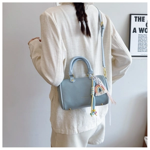Detail of light blue pebble leather Boston bag with gold hardware and rainbow charm