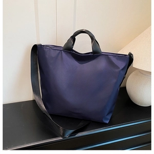 Detail of a large purple tote bag made of waterproof nylon on a dark surface