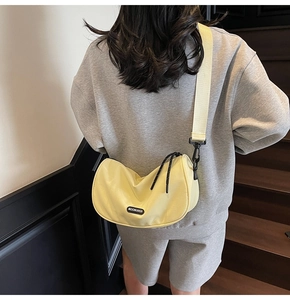 Close-up of pale yellow moon bag showing MOONLERSA label and wide fabric shoulder strap