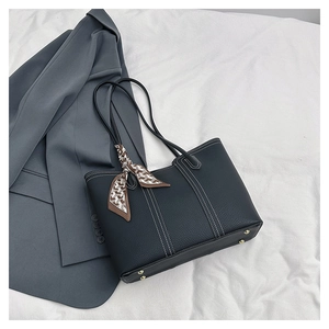 Detail of black pebbled leather tote with contrast stitching and silk scarf accessory
